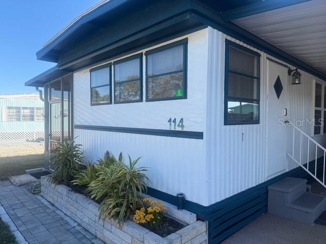 The exterior of a white mobile home features dark blue trim, windows, and a front entrance — 420 49TH STREET E UNIT 114, PALMETTO, FL