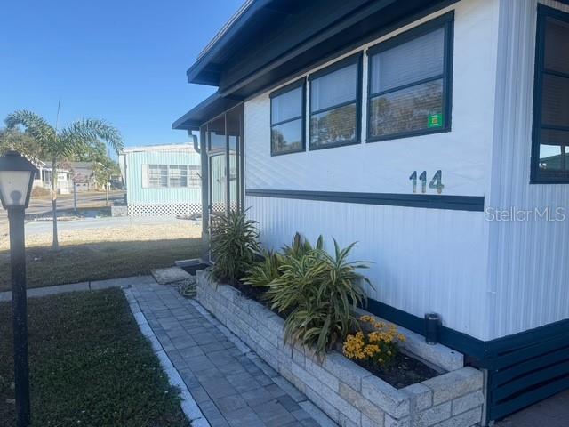 A white mobile home exterior features a stone planter box and a paved walkway — 420 49TH STREET E UNIT 114, PALMETTO, FL