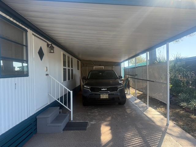 A black SUV is parked under a covered carport attached to a mobile home — 420 49TH STREET E UNIT 114, PALMETTO, FL