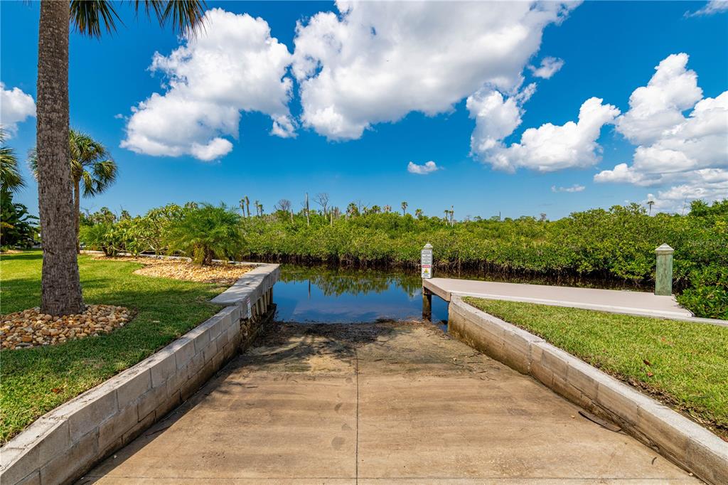 A concrete boat ramp leads into a narrow waterway surrounded by lush green vegetation — 8727 BETTY STREET, PORT RICHEY, FL