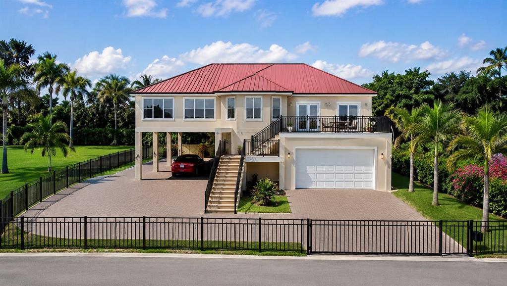 A two-story elevated house with a red metal roof and a paved driveway — 8727 BETTY STREET, PORT RICHEY, FL