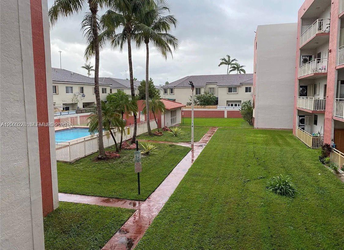 An outdoor view shows a grassy courtyard, a swimming pool, and a multi-story apartment building — 8425 NW 8th St # 306, Miami FL 33126, MIAMI, FL