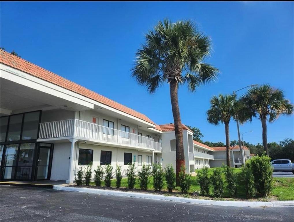 A two-story motel building with a white exterior, a tiled roof, and palm trees — 5367 W IRLO BRONSON MEMORIAL HIGHWAY UNIT 2-214, KISSIMMEE, FL