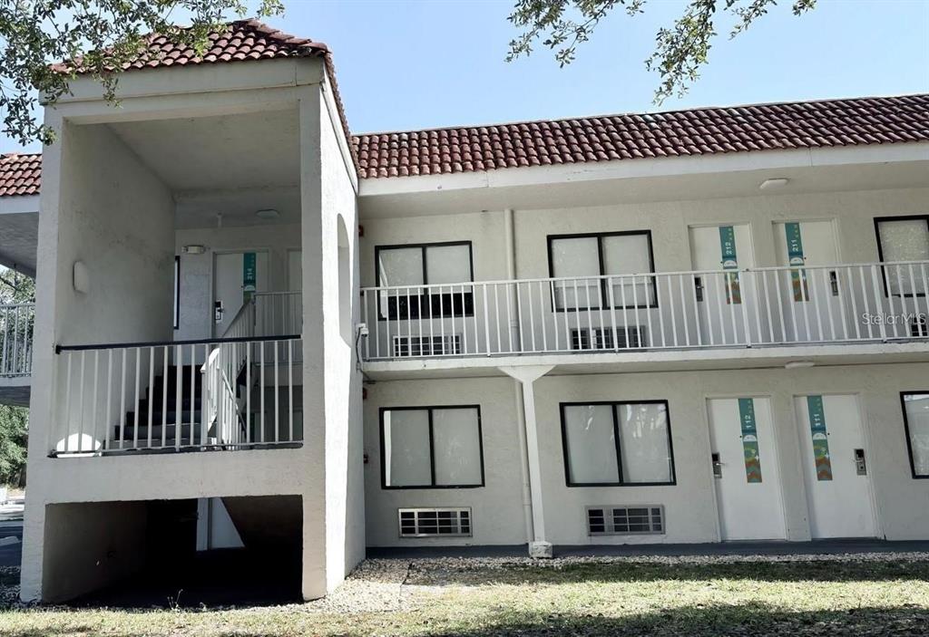 A two-story exterior corridor apartment building with white stucco walls and a red tile roof — 5367 W IRLO BRONSON MEMORIAL HIGHWAY UNIT 2-214, KISSIMMEE, FL