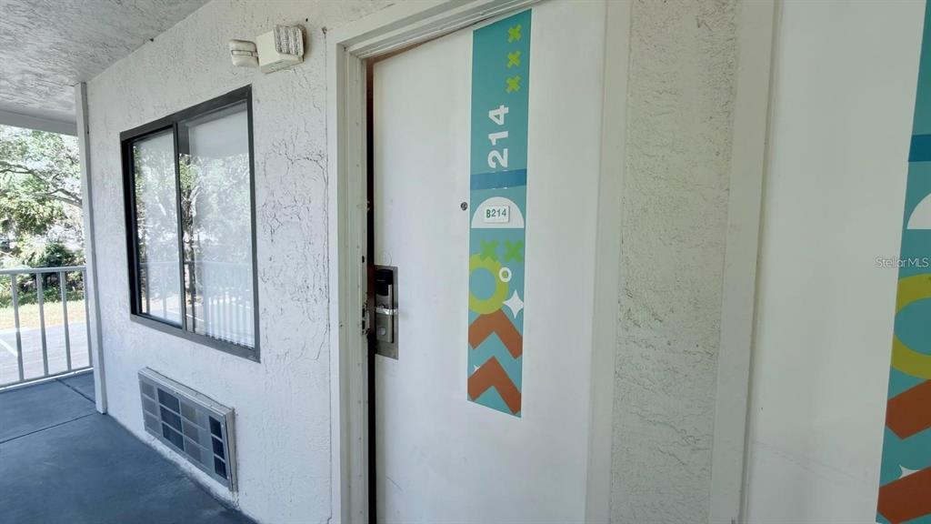 A white exterior door with a decorative blue and orange graphic and number 214 — 5367 W IRLO BRONSON MEMORIAL HIGHWAY UNIT 2-214, KISSIMMEE, FL