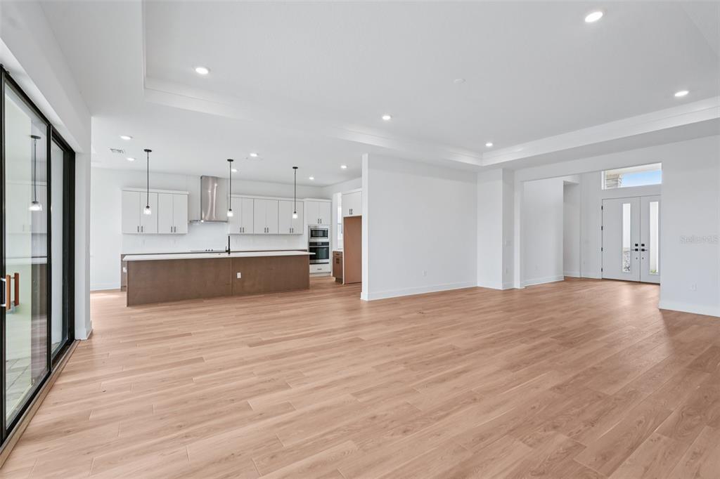 An open-concept kitchen and living area features white cabinetry, a large island, and wood flooring — 12652 IVORY TUSK LANE, SPRING HILL, FL