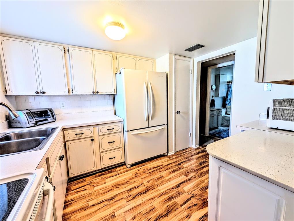 A kitchen features white cabinets, a white refrigerator, and wood-look flooring — 5855 PALM LANE UNIT B21, BRADENTON, FL