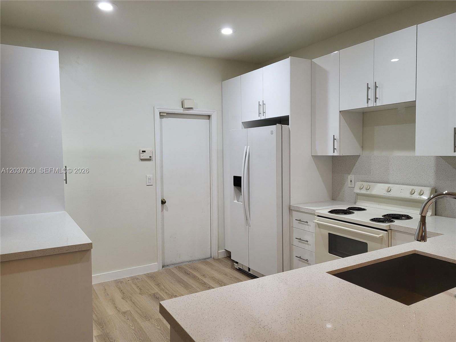 A kitchen features white cabinets, light countertops, a white refrigerator, and a white stove — 1990 Madeira Dr, Weston FL 33327, WESTON, FL
