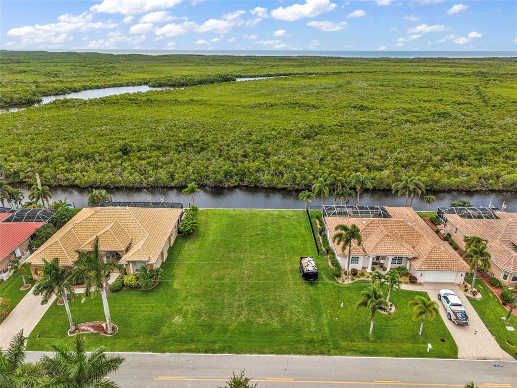 An aerial view shows a vacant grassy lot situated between two houses facing a waterway — 645 MACEDONIA DRIVE, PUNTA GORDA, FL