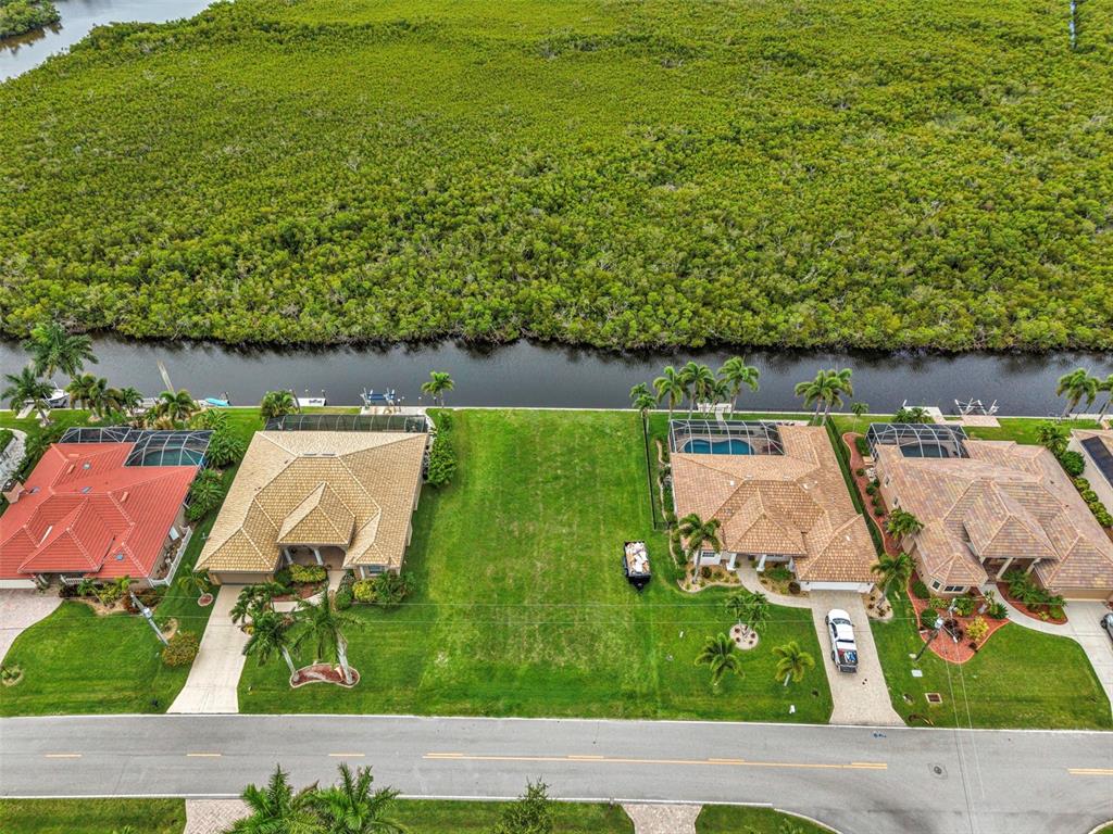 An aerial view shows a vacant residential lot situated between two houses along a canal — 645 MACEDONIA DRIVE, PUNTA GORDA, FL