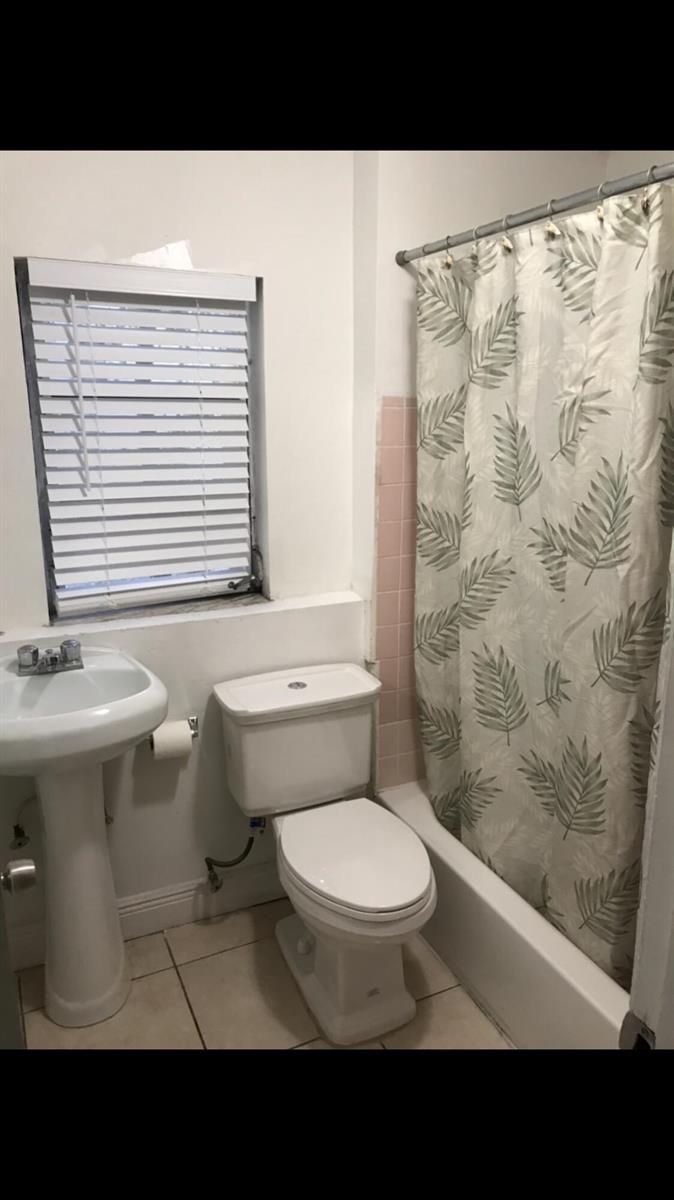 A bathroom featuring a pedestal sink, a toilet, and a shower with a leaf-patterned curtain — 1021 SW 5th Street, Miami FL 33130, MIAMI, FL