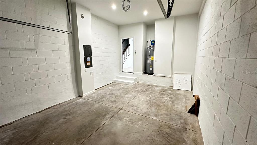 This garage features white painted concrete block walls, a concrete floor, and a water heater — 9040 OCEAN TIDE WAY, KISSIMMEE, FL