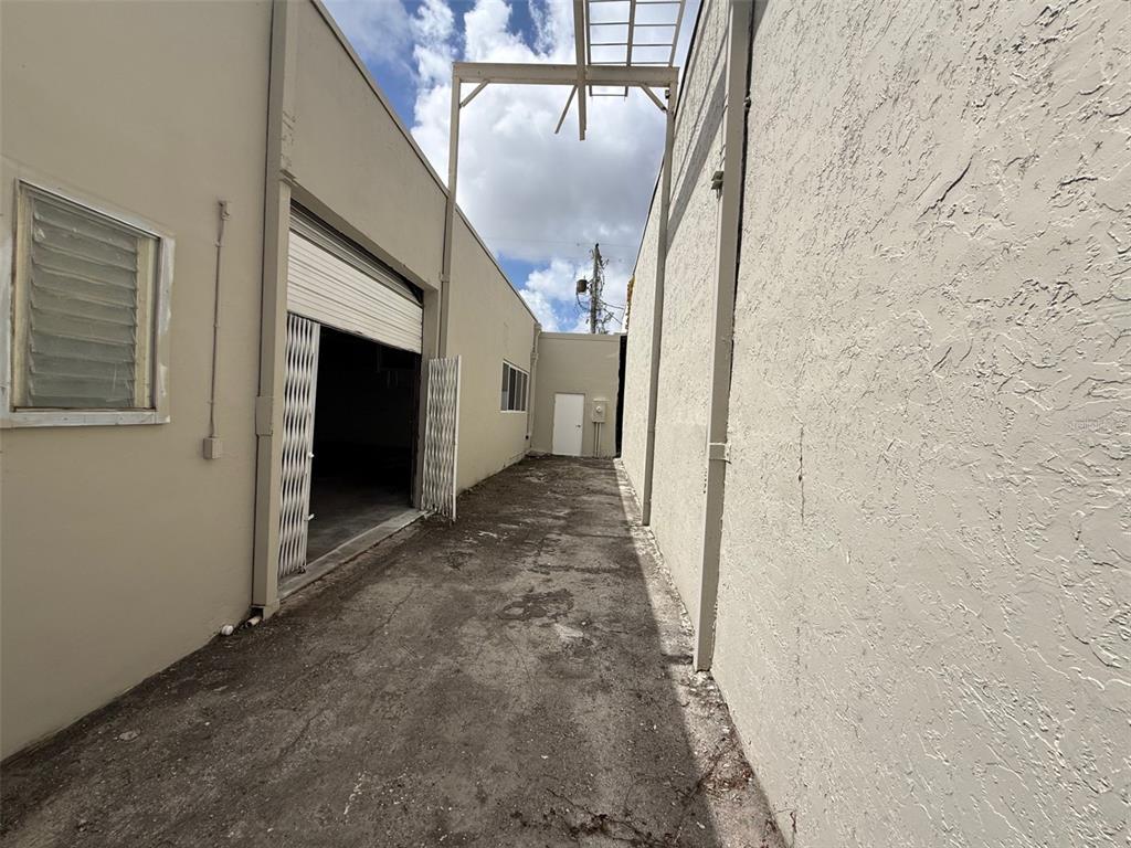 A narrow outdoor alleyway sits between two beige stucco commercial building walls — 14020 NW 19TH AVENUE, OPA LOCKA, FL