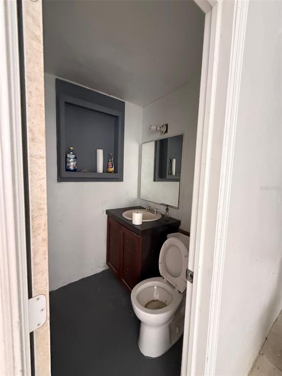 A small bathroom features a dark wood vanity, a white toilet, and a recessed wall shelf — 14020 NW 19TH AVENUE, OPA LOCKA, FL