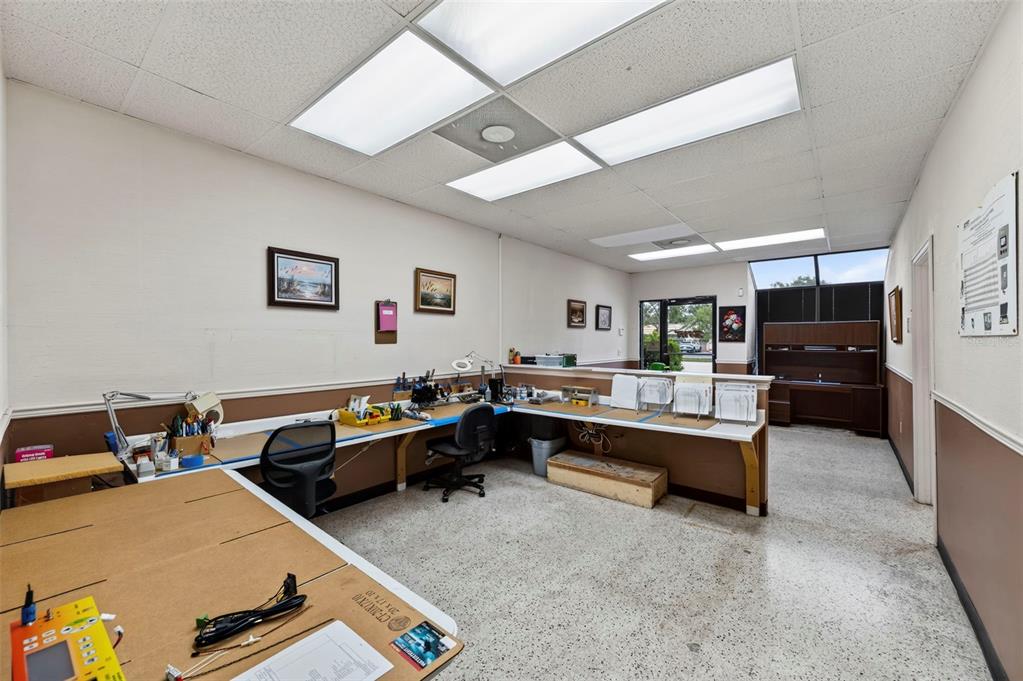 An office or workshop space features a long L-shaped desk, drop ceiling, and speckled flooring — 3632 CENTRAL AVENUE, ST PETERSBURG, FL