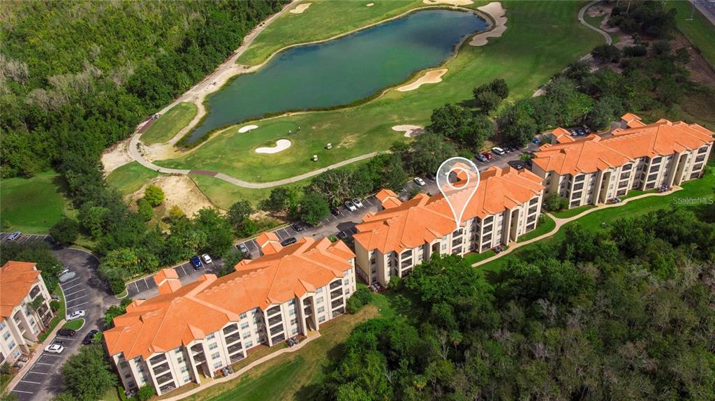 An aerial view shows a multi-story apartment complex with orange roofs near a golf course — 8010 TUSCANY WAY UNIT 5105, DAVENPORT, FL