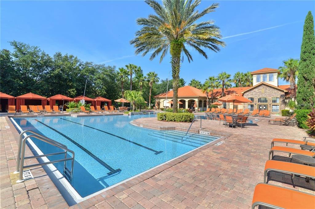 A swimming pool with lounge chairs and umbrellas sits in front of a clubhouse building — 8010 TUSCANY WAY UNIT 5105, DAVENPORT, FL