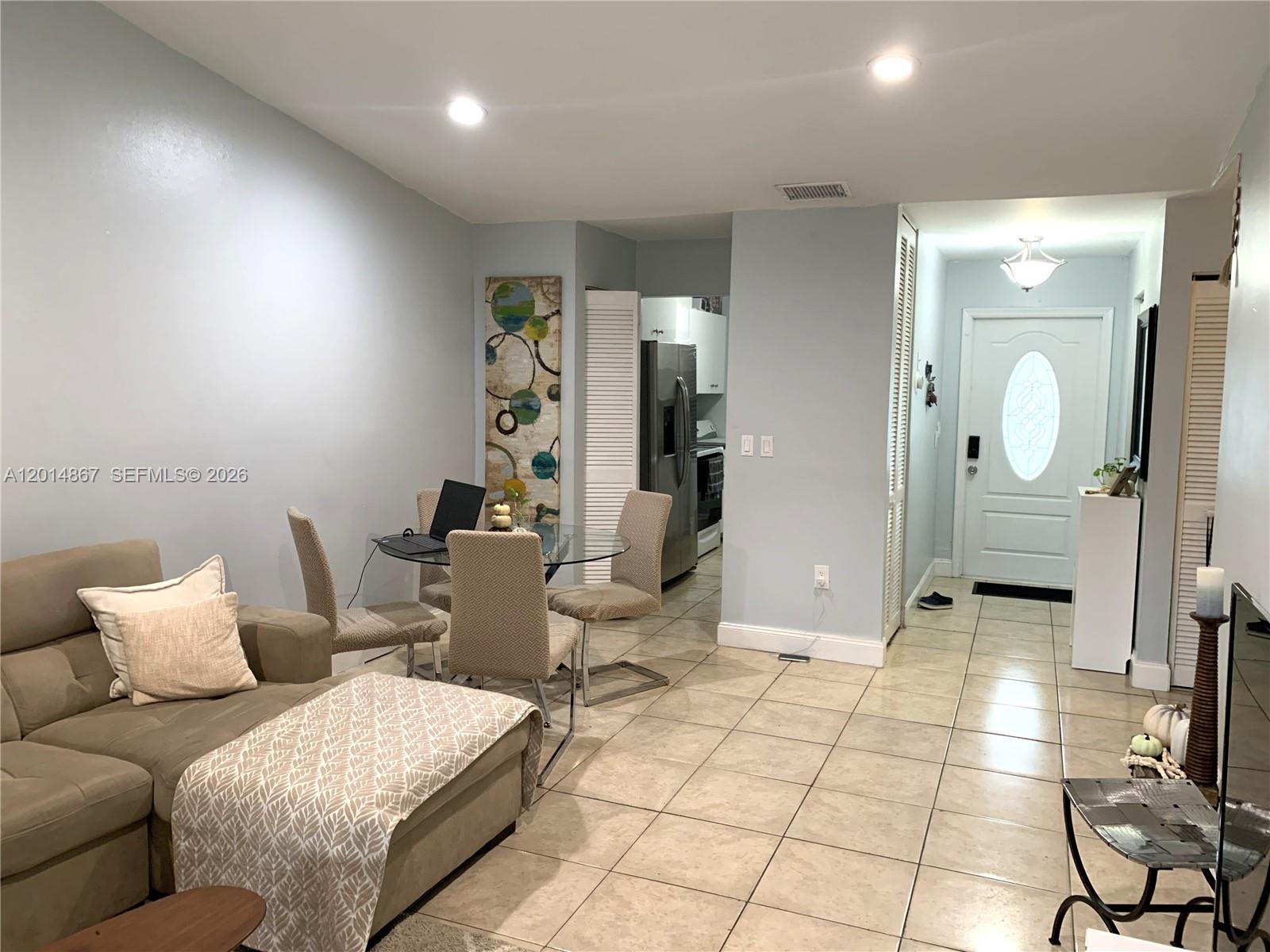 A living room and dining area with light blue walls, tile flooring, and a front door — 4904 SW 139th Ct, Miami FL 33175, MIAMI, FL