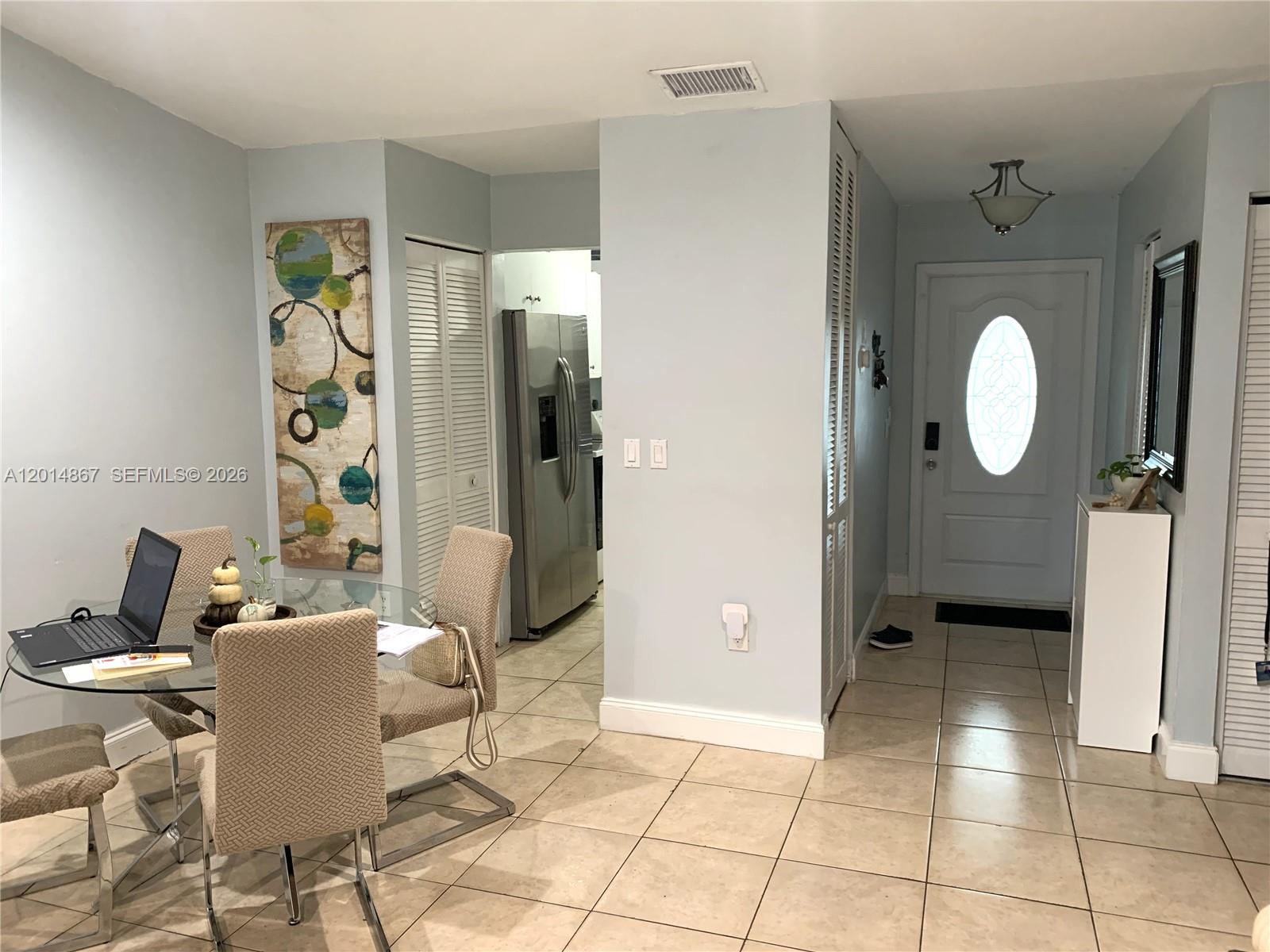 A dining area with a glass table and chairs leads to a kitchen and entryway — 4904 SW 139th Ct, Miami FL 33175, MIAMI, FL