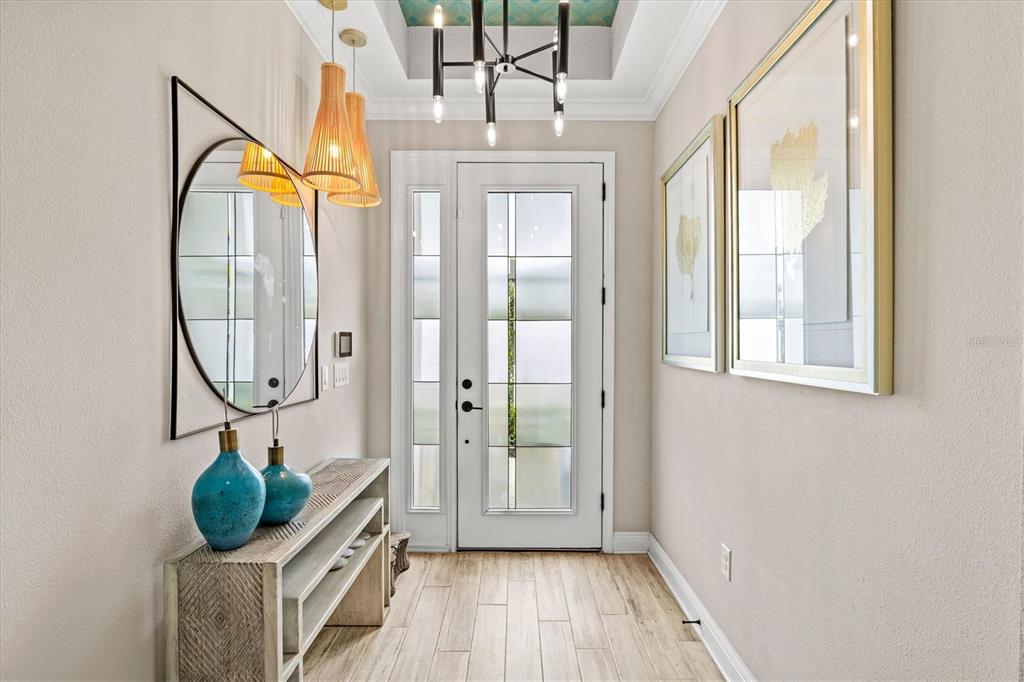 A bright entryway features a white front door, wood-look tile flooring, and modern light fixtures — 5516 NORTHERN JUNIPER COURT, SARASOTA, FL