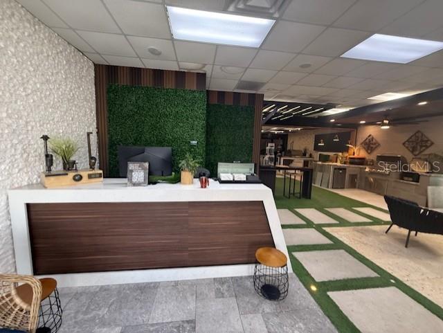 A modern showroom features a reception desk, a green wall, and indoor patio-style flooring — 3852 L B MCLEOD ROAD, ORLANDO, FL