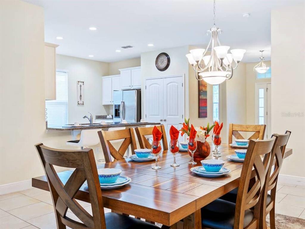 A dining room with a wooden table and chairs sits in front of an open kitchen — 4408 ACORN COURT, DAVENPORT, FL