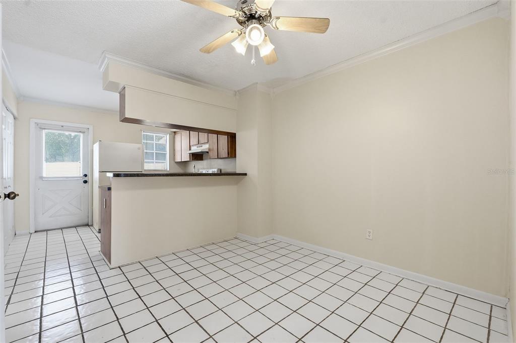 A dining area with white tiled floors, a ceiling fan, and a pass-through kitchen counter — 6620 121ST AVENUE UNIT 1, LARGO, FL