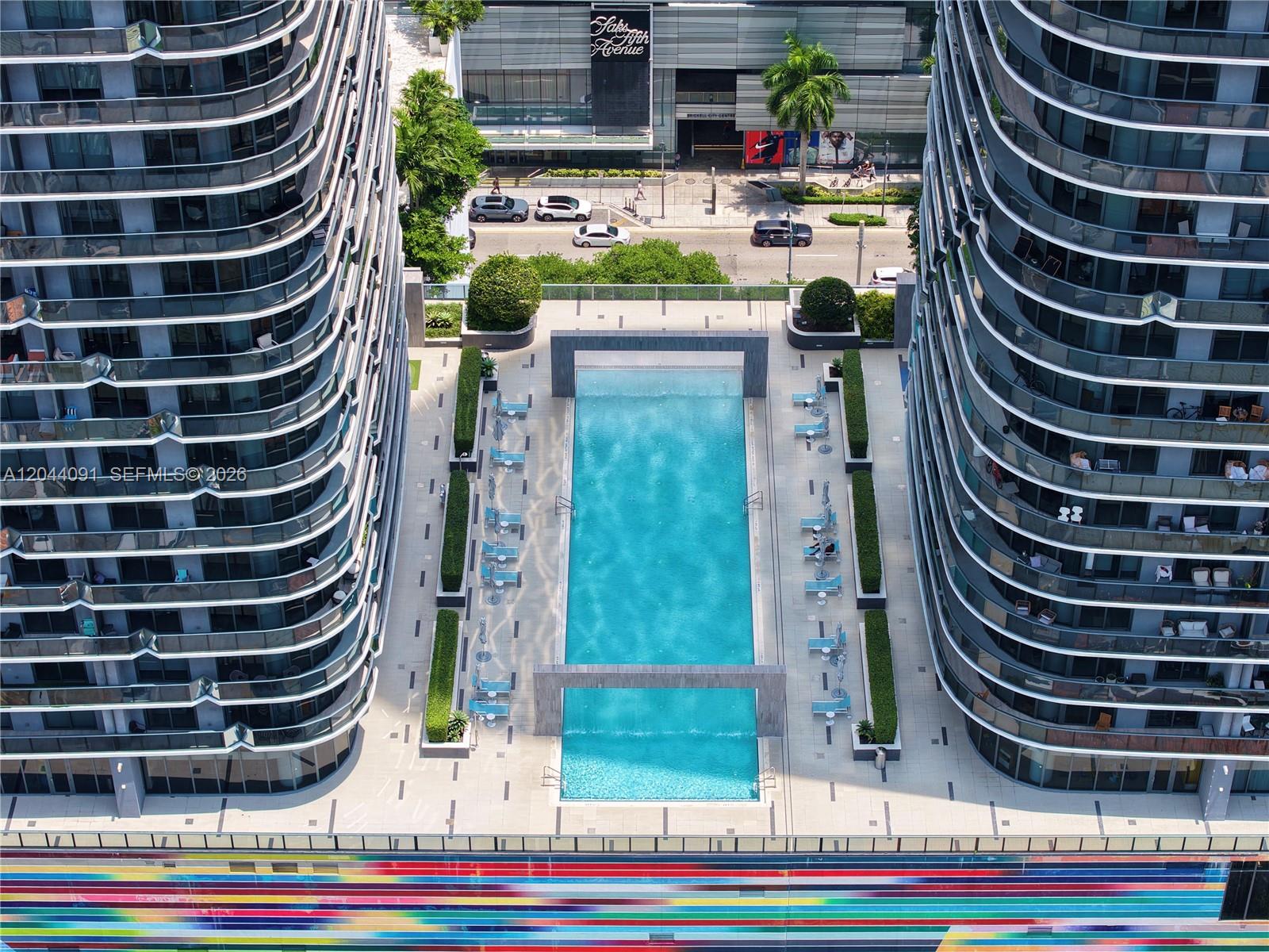 An aerial view shows a rectangular swimming pool situated between two modern high-rise apartment buildings — 55 SW 9th St # 2208, Miami FL 33130, MIAMI, FL