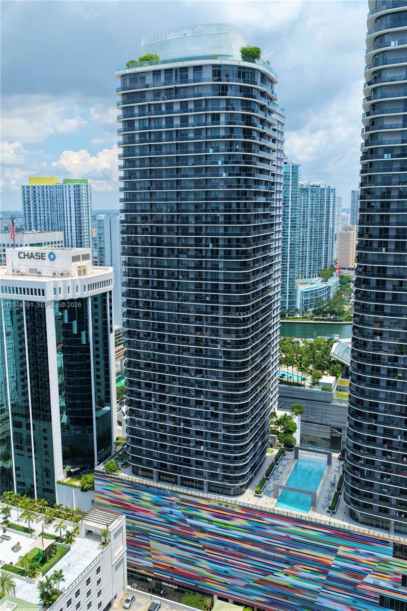 An aerial view shows a tall residential skyscraper with a colorful, striped parking garage base — 55 SW 9th St # 2208, Miami FL 33130, MIAMI, FL