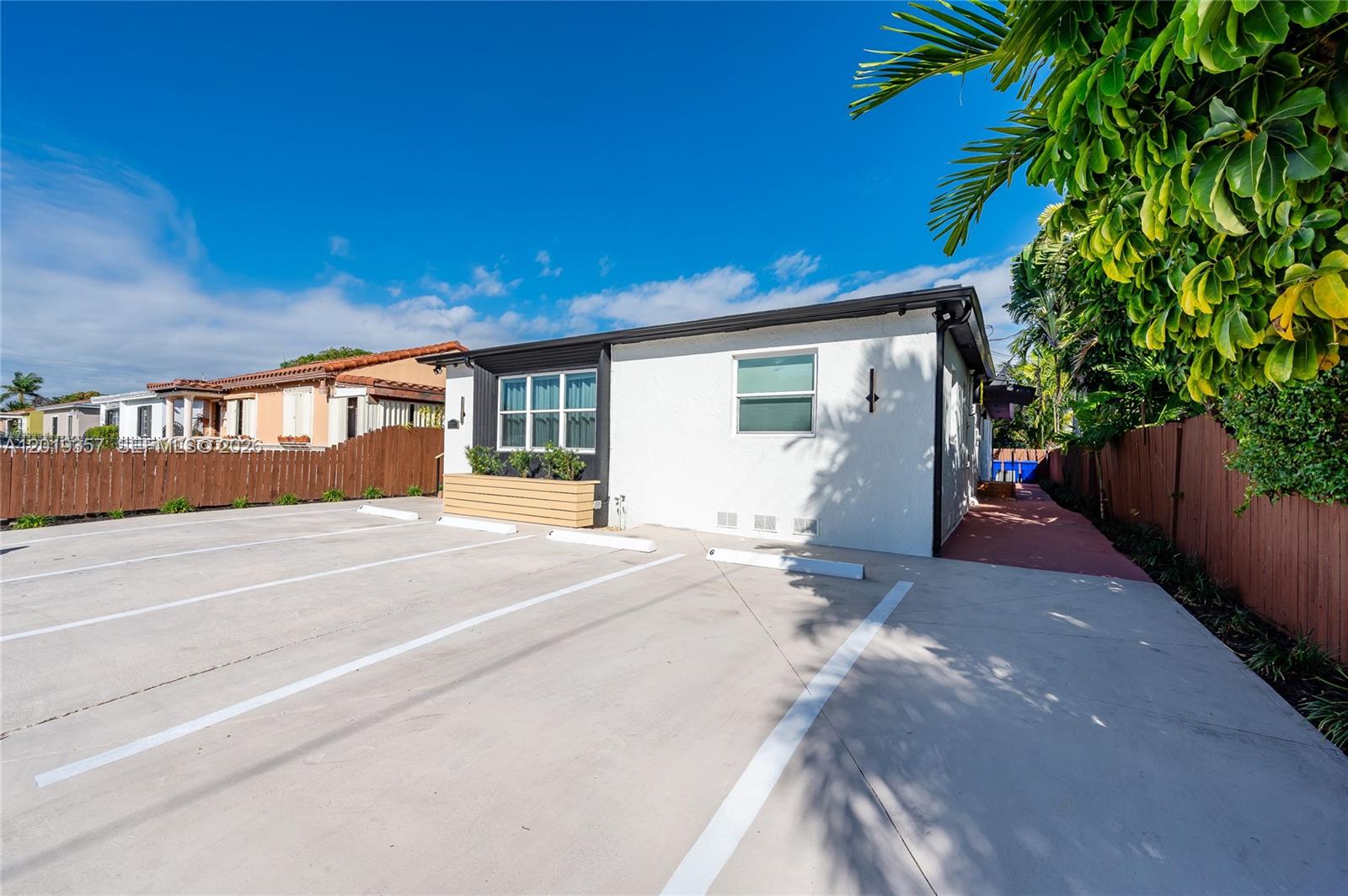 A white single-story building features a paved parking lot and a wooden fence — 3321 NW 19th Ter, Miami FL 33125, MIAMI, FL