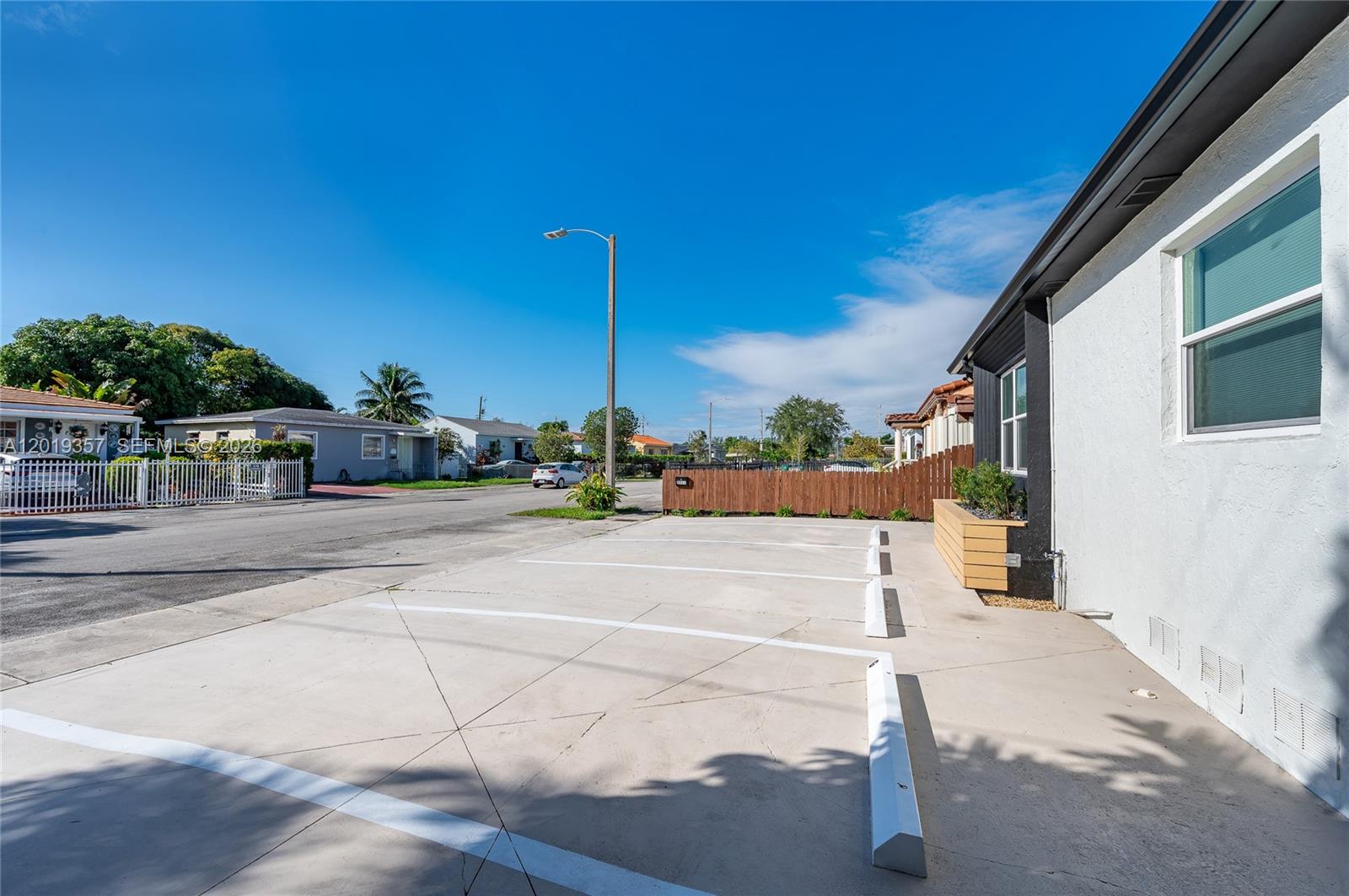 An exterior view shows a concrete parking area with white wheel stops beside a building — 3321 NW 19th Ter, Miami FL 33125, MIAMI, FL