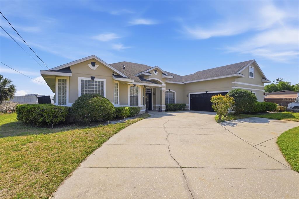 A single-story house with a beige exterior, a dark roof, and a concrete driveway at dusk — 1051 DUNBAR AVENUE, SANFORD, FL