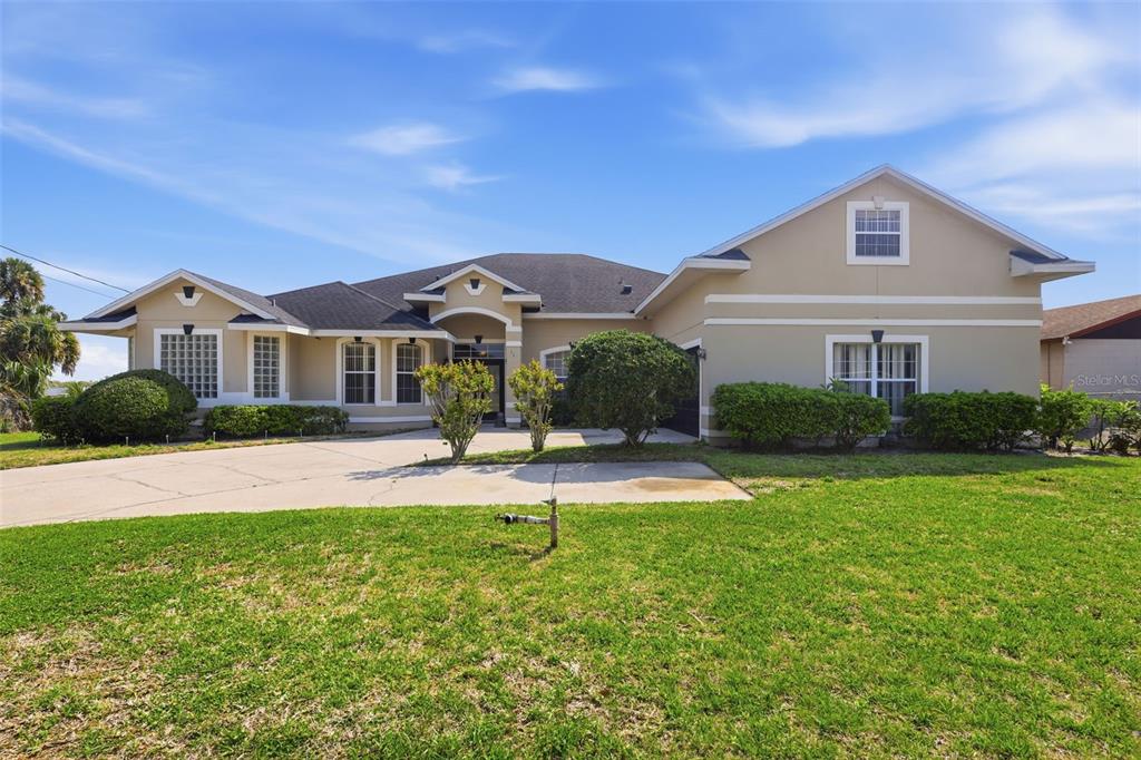 A tan single-story house with a concrete driveway and a dark two-car garage — 1051 DUNBAR AVENUE, SANFORD, FL
