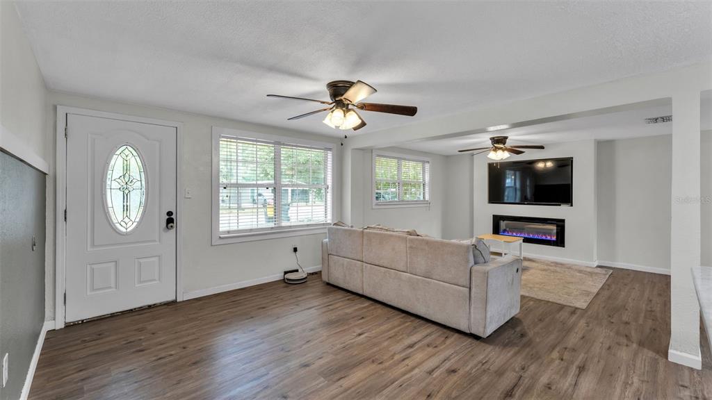 A living room features wood-look flooring, a light-colored sofa, a fireplace, and two ceiling fans — 217 4TH JPV STREET, WINTER HAVEN, FL