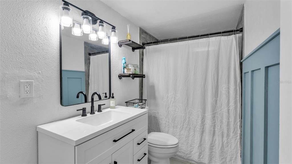 A bathroom features a white vanity, a black-framed mirror, and a white shower curtain — 217 4TH JPV STREET, WINTER HAVEN, FL