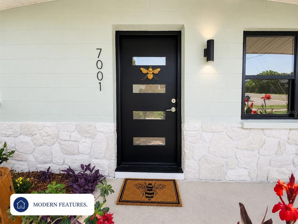 A concrete walkway leads along the side of a house with stone siding and landscaping — 7001 59TH STREET N, PINELLAS PARK, FL