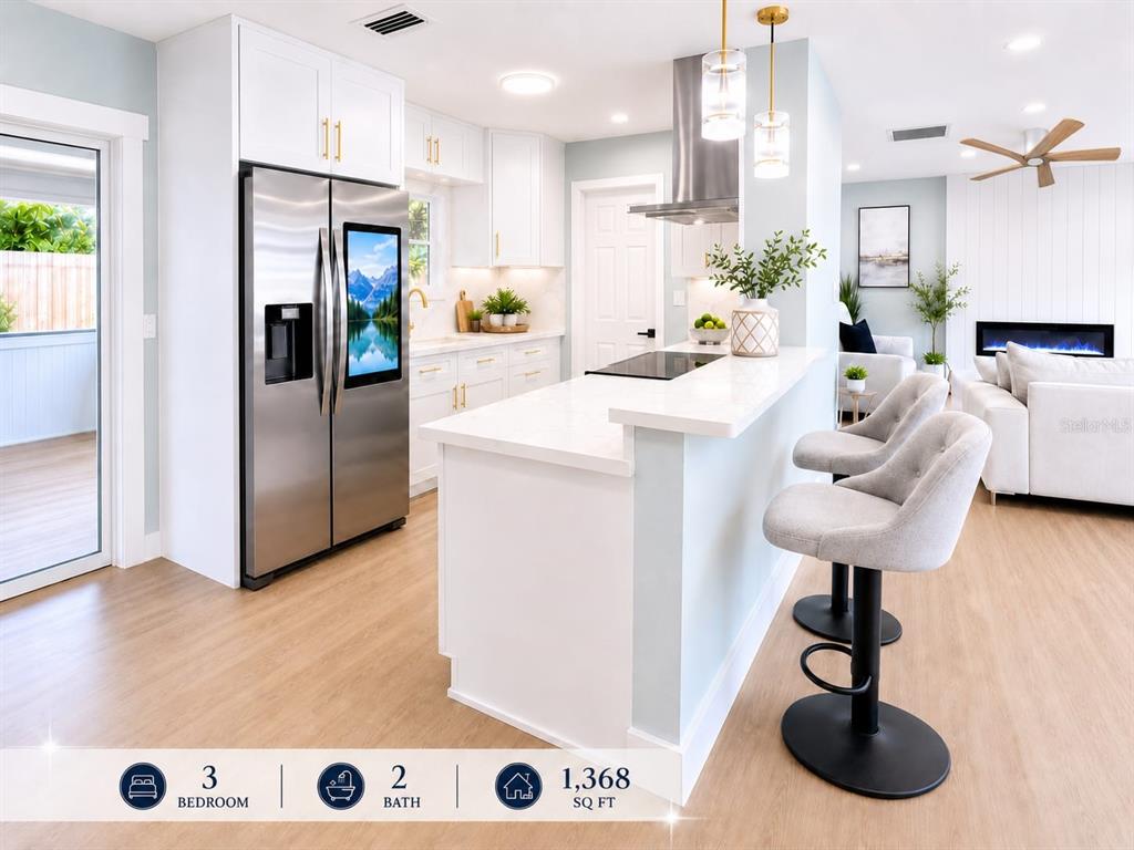 A modern kitchen with white cabinets and light wood floors opens to a living area — 7001 59TH STREET N, PINELLAS PARK, FL