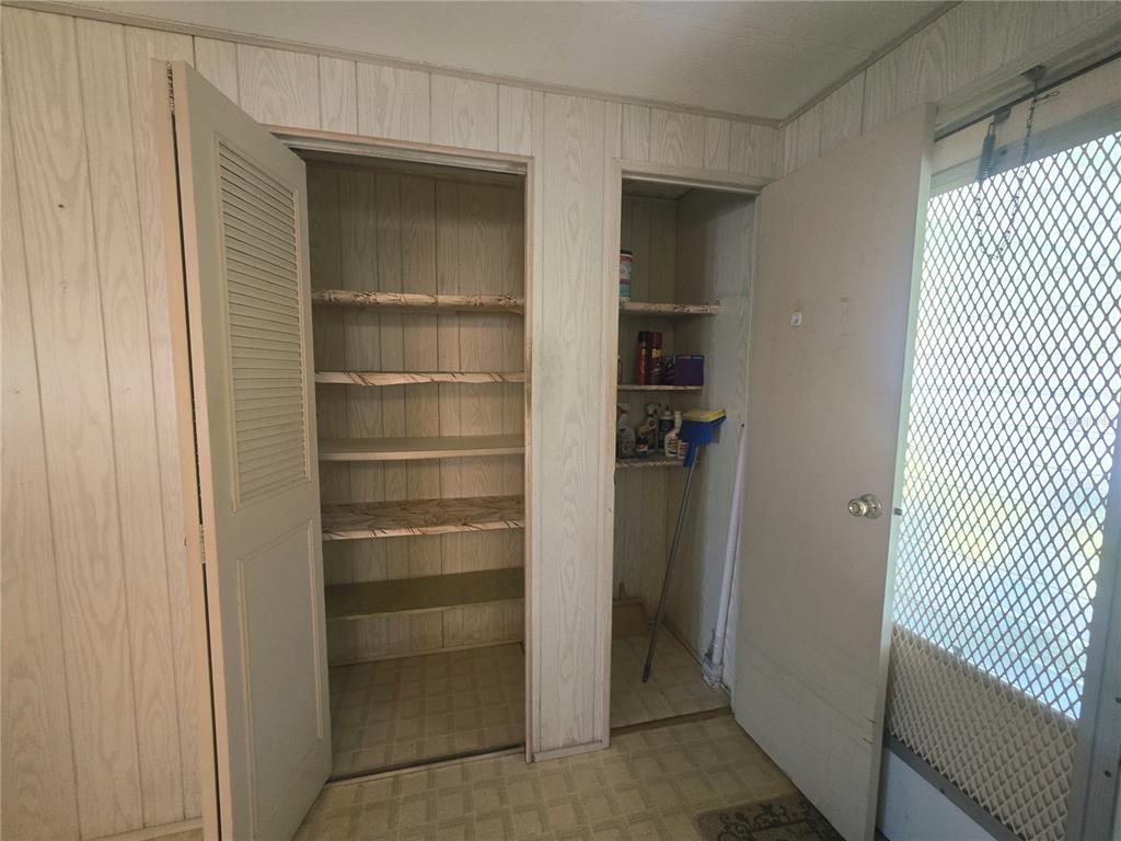 A room features wood-paneled walls, two open storage closets with shelves, and a screen door — 39820 US HIGHWAY 19 N UNIT 182, TARPON SPRINGS, FL
