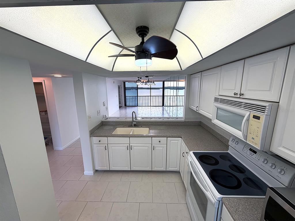 A kitchen with white cabinets, a grey countertop, and a view of the water — 4620 BAY BOULEVARD UNIT 1122, PORT RICHEY, FL
