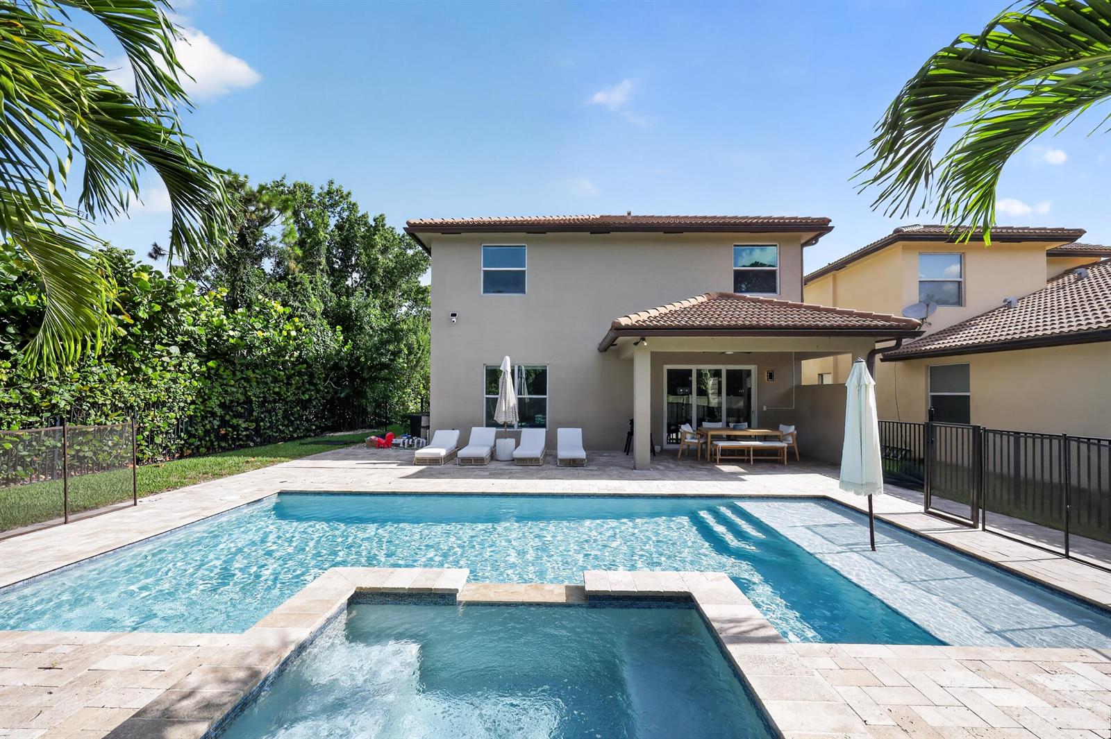A backyard features a swimming pool, a hot tub, and a covered patio with furniture — 7050 Limestone Cay Road, FL 33458, FL