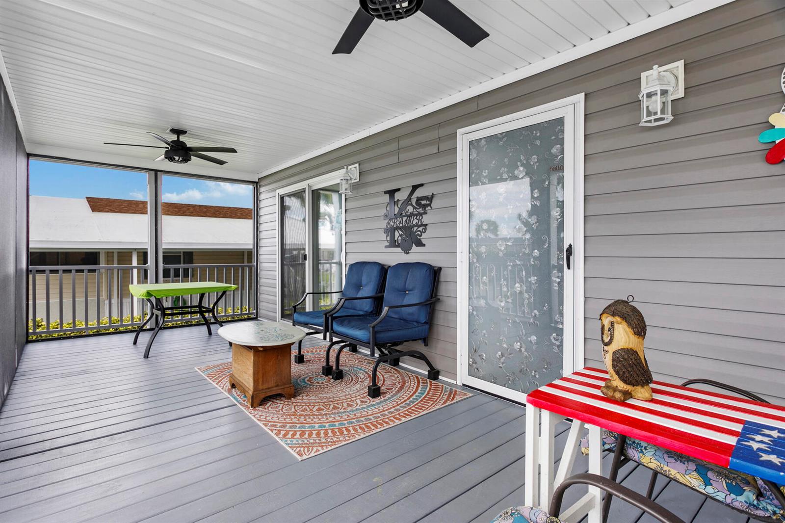 A covered porch features gray siding, a patterned rug, blue chairs, and a screen enclosure — 37006 Exuma Bay, Boynton Beach FL 33436, BOYNTON BEACH, FL