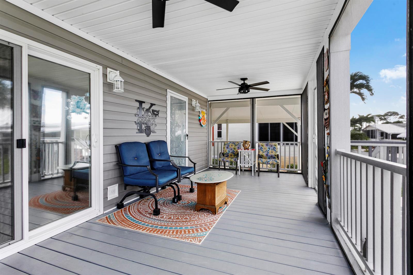 A screened-in porch features gray wood-look flooring, a blue loveseat, and two patterned chairs — 37006 Exuma Bay, Boynton Beach FL 33436, BOYNTON BEACH, FL
