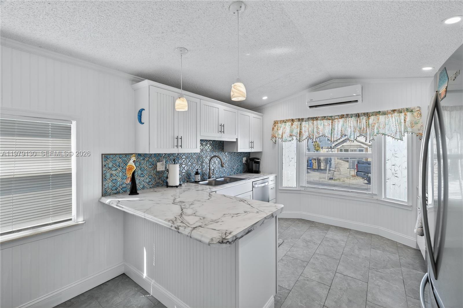 A kitchen features white cabinets, a marble-patterned countertop, and a blue patterned tile backsplash — 701 Spanish Main Dr # 536, Lower Keys FL 33042, LOWER KEYS, FL