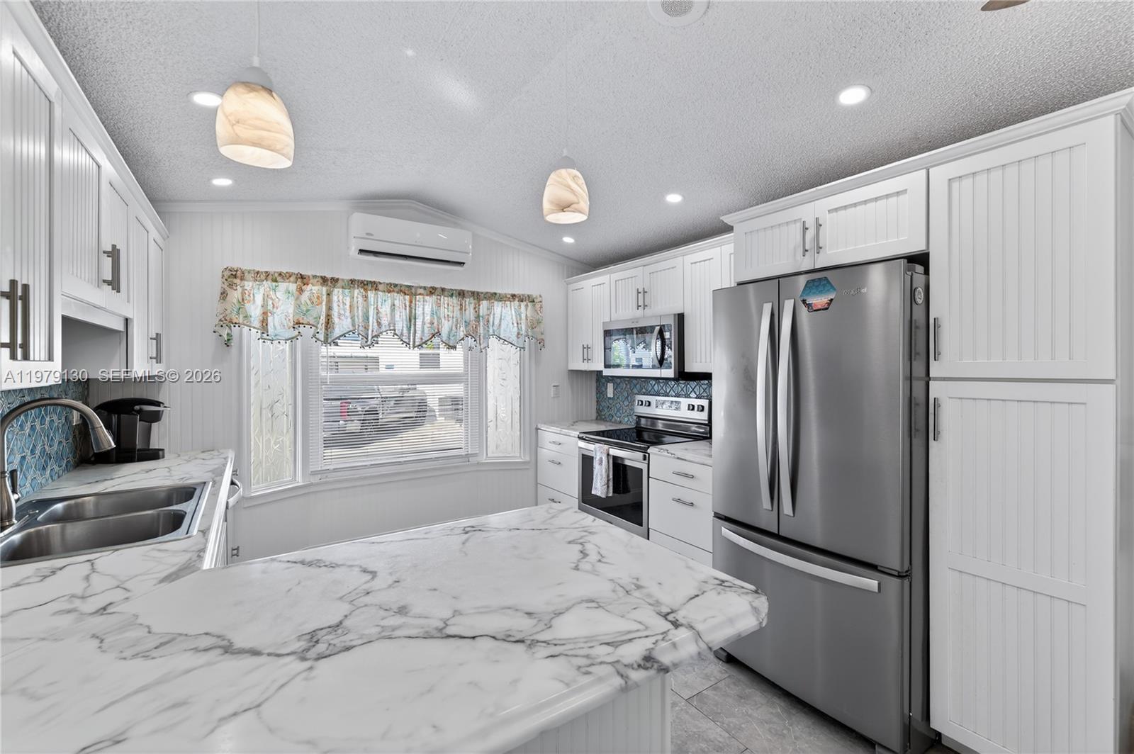 A kitchen features white cabinetry, marble-look countertops, stainless steel appliances, and a blue tiled backsplash — 701 Spanish Main Dr # 536, Lower Keys FL 33042, LOWER KEYS, FL