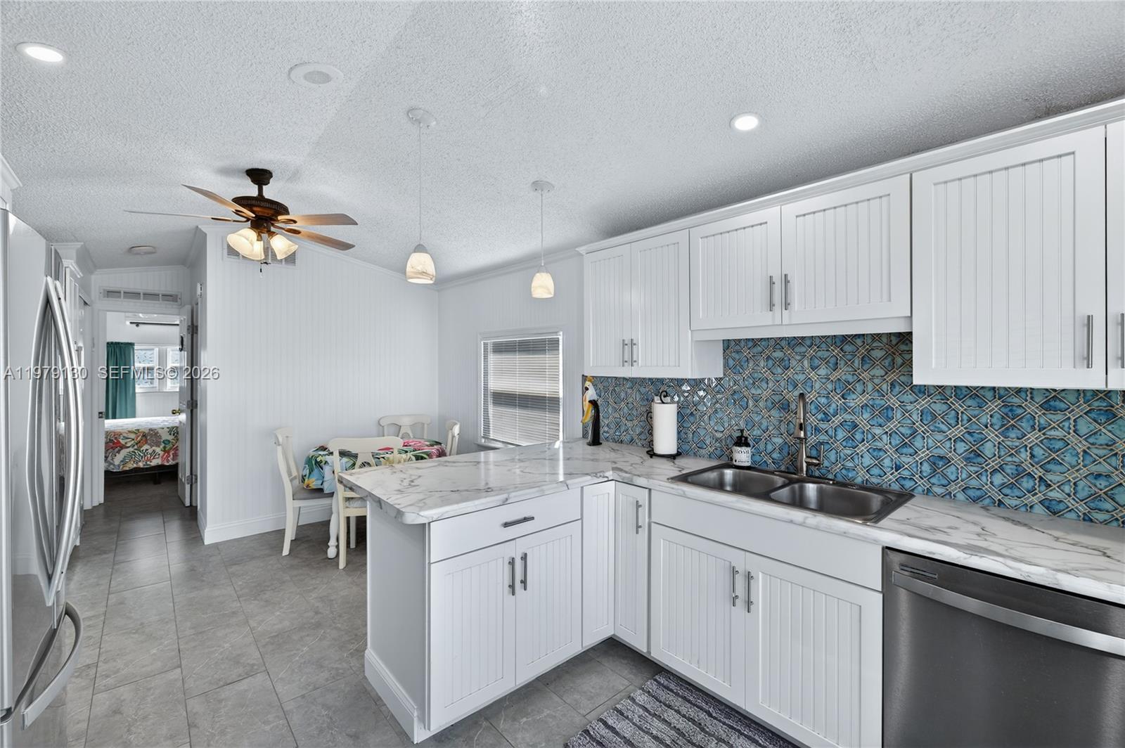 A kitchen with white beadboard cabinets, marble-look countertops, and a blue patterned tile backsplash — 701 Spanish Main Dr # 536, Lower Keys FL 33042, LOWER KEYS, FL