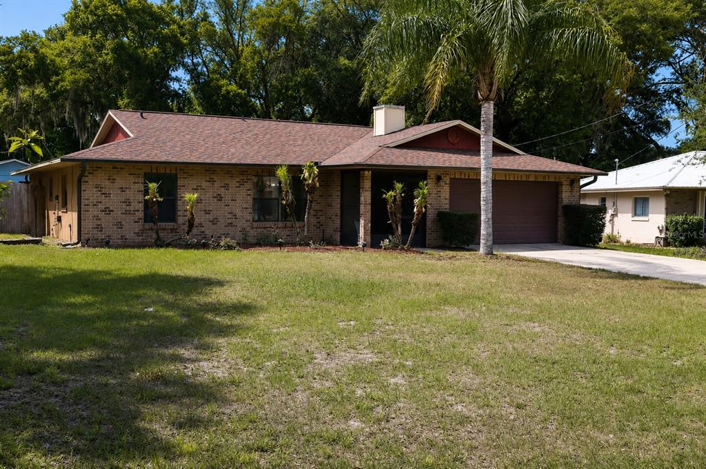 A single-story brick house with a brown shingled roof and an attached garage — 226 COUNCIL BLUFFS DRIVE, DELTONA, FL