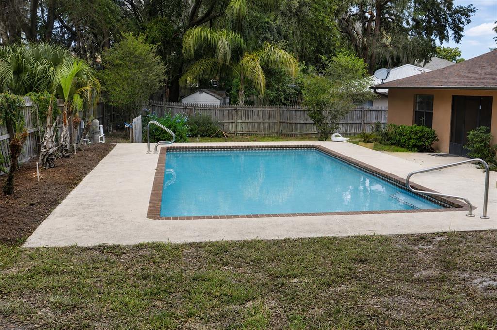 A rectangular backyard swimming pool with a concrete deck and metal handrails — 226 COUNCIL BLUFFS DRIVE, DELTONA, FL