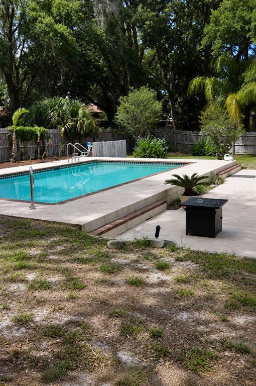 A backyard features an elevated rectangular swimming pool with a concrete deck and fire pit — 226 COUNCIL BLUFFS DRIVE, DELTONA, FL