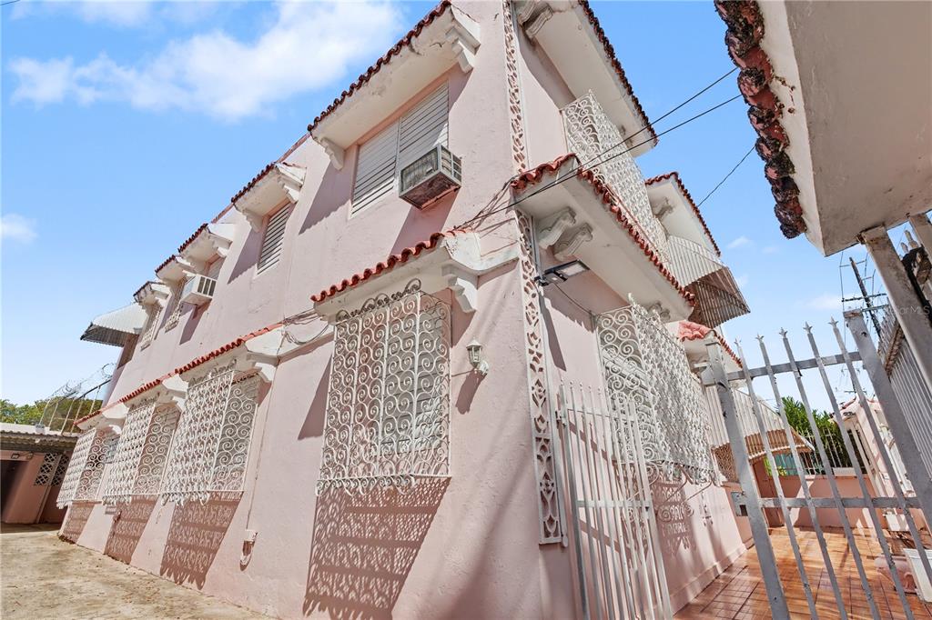 A low-angle exterior view of a pink multi-story building featuring decorative white metal window grilles — 508 AVE. SAGRADO CORAZON AVENUE, SAN JUAN, PR