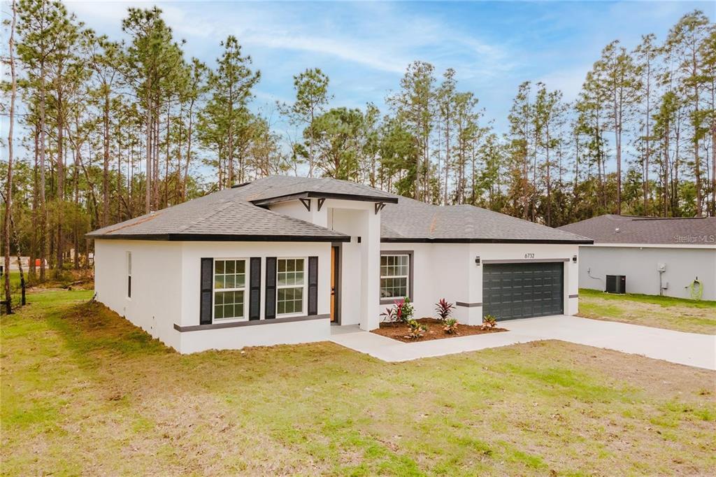 A single-story white house with a dark roof, black shutters, and a two-car garage — 6732 SW 132ND STREET, OCALA, FL
